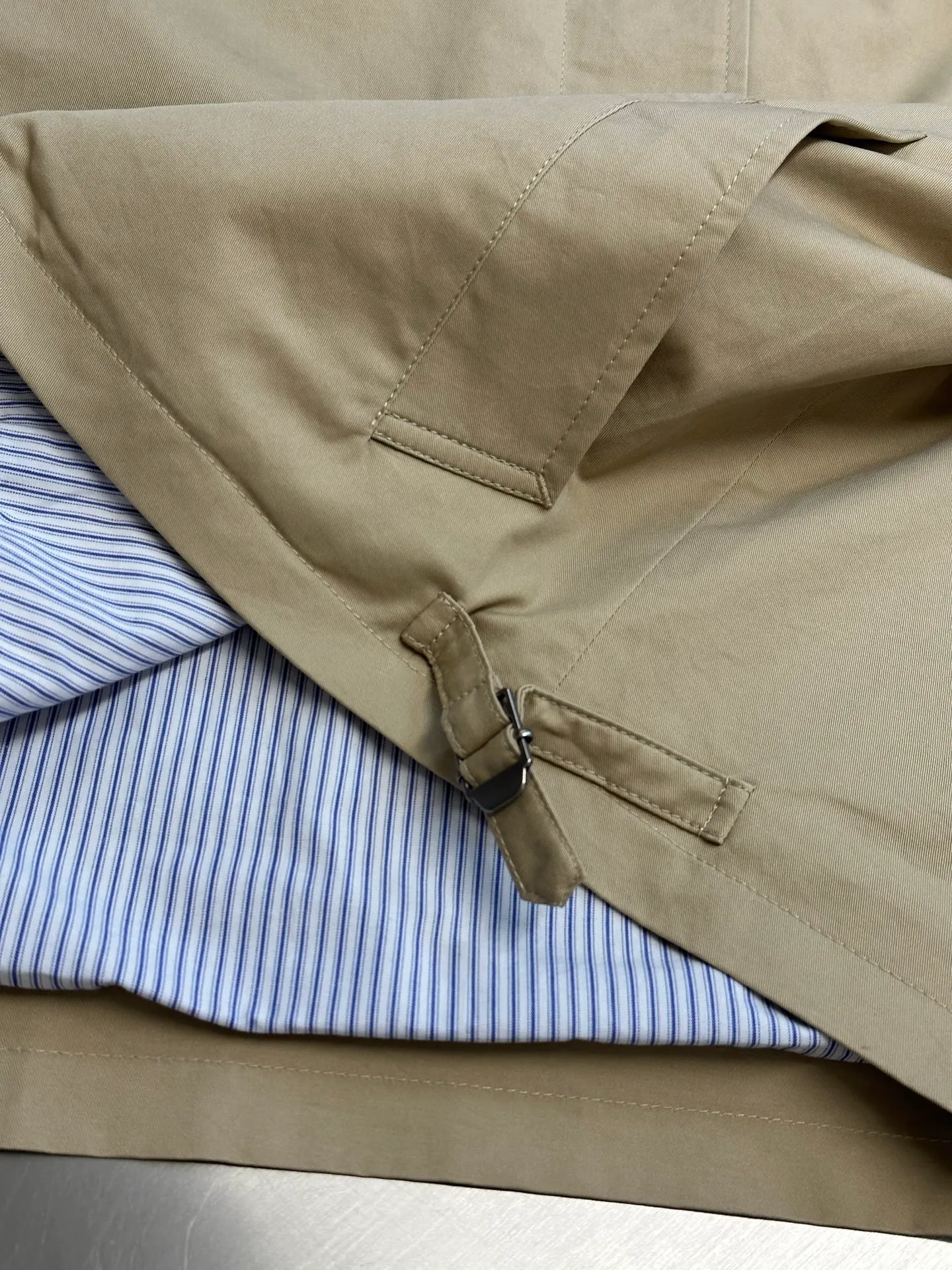 Ac Hot Sale genuine two-piece jacket. The main body is made of high-density twill cotton poplin. It has been processed by pre-shrunk washing process. The cloth surface is smooth and clean, with a matte and soft workwear texture. The stiffness is just right. The short version can be held up three-dimensionally and is not easy to collapse and wrinkle. It is suitable for daily commuting and outdoor use. The inner shirt is made of yarn-dyed blue and white striped cotton. The yarn-dyed stripes have clear texture and will not turn white or smudged after washing. The fabric surface is breathable and dry, and the collar and cuffs are folded and exposed to form contrasting color layers. The difficulty of the whole piece lies in the combined sewing of two fake pieces. The shirt collar and jacket collar are double-stitched and seamed. The collar corners are shaped and hemmed, and the folding shape is neat and will not collapse and curl. The placket adopts a double-layer structure of zipper + hidden buckle windproof fabric. The inner and outer layers of fabric are aligned and sewn together, and the wiring is even and fine. There are adjustable tabs on both sides of the hem, which can be freely tightened to suit different styles. The back printing adopts embossed relief technology, which blends into the fabric and is low-key and unobtrusive. The zipper is made of nylon zipper with metal teeth. The teeth are polished smoothly and will not get stuck after repeated pulling. The zipper headband has brand engraved details. The buttons are divided into two systems: the outer part is made of horn dark brown resin buttons with natural texture and high-end matte texture; the inner shirt is equipped with Cream White pearlescent four-eye buttons, echoing the blue and white striped fabric. size：xs s m l